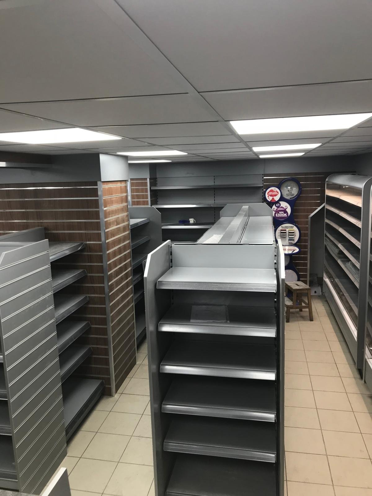 Convenience store interior with silver shelving and wood-effect panelling