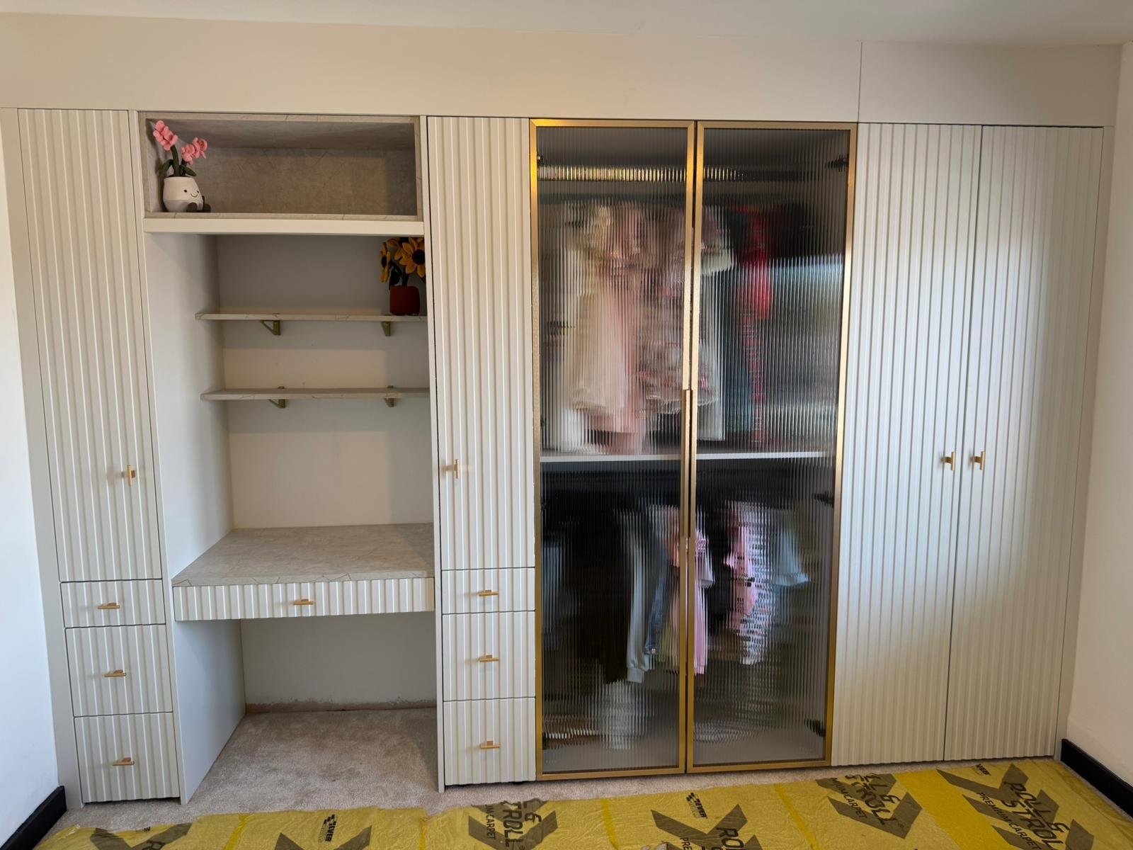 Fitted wardrobe combining fluted doors, open shelving and a built-in dressing area